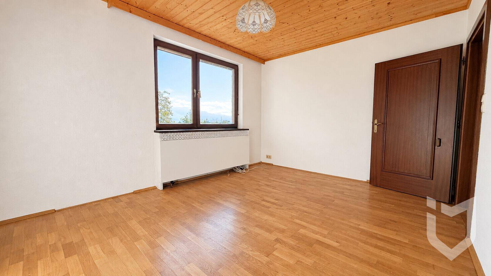 Schlafzimmer mit Holzboden, Fenster und Blick auf die Landschaft.