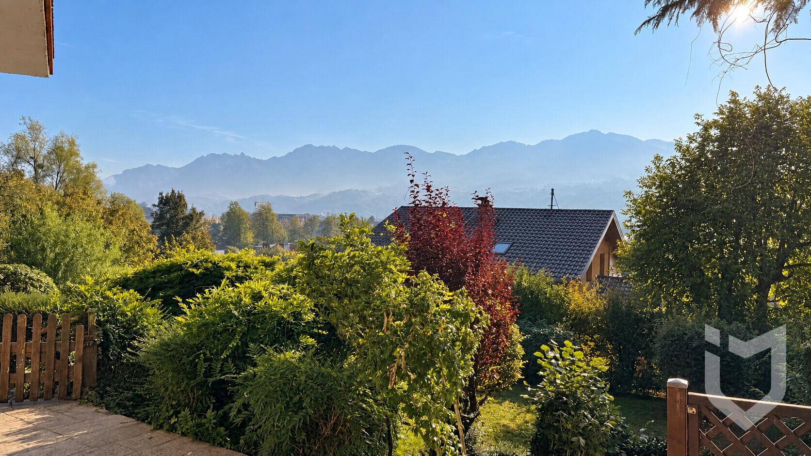 Gepflegter Gartenbereich mit Hecken und weitem Bergblick.