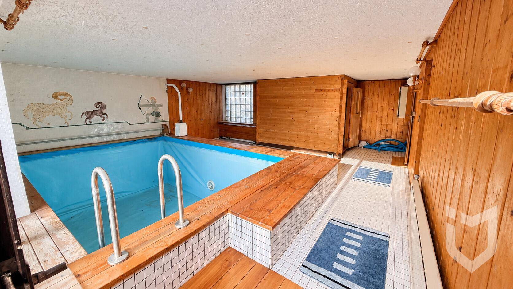 Innenpoolbereich mit Holzverkleidung und Fliesenboden.