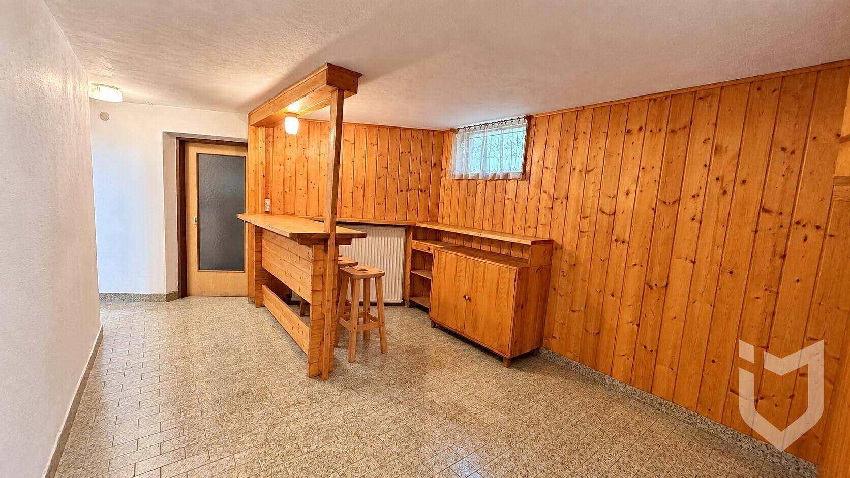 Ausgebauter Kellerraum mit Holzvertäfelung und einer Bar.