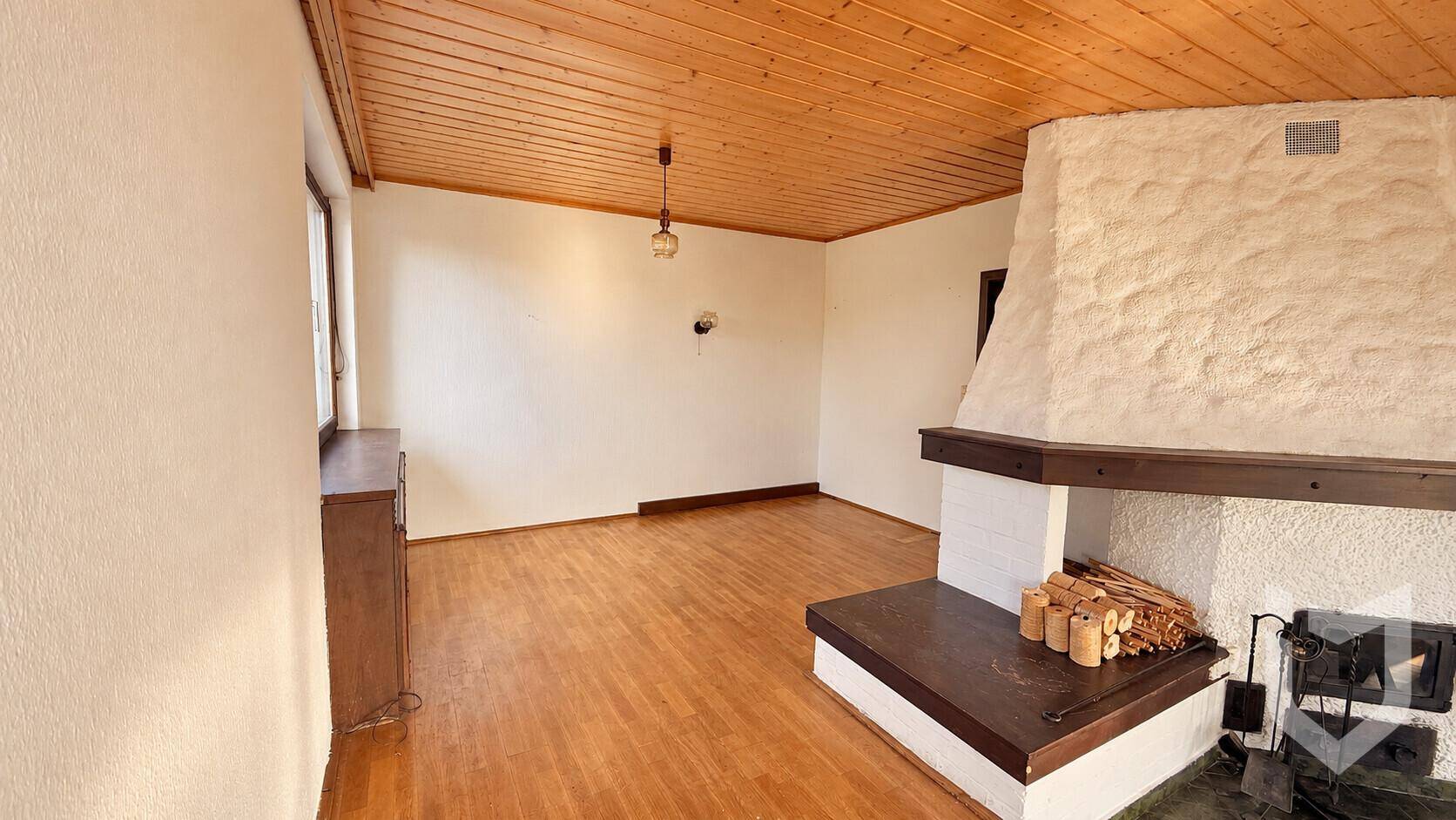 Gemütliches Wohnzimmer mit Holzboden und traditionellem Kamin.