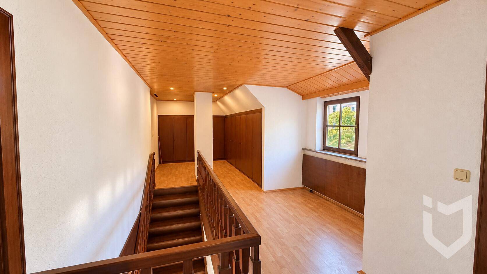 Heller Flur mit Holzdecke, Holztreppe und Laminatboden.