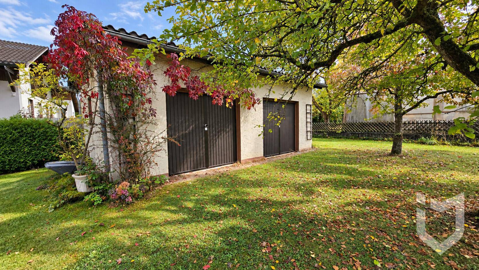 Freistehende Garage mit zwei Holztoren und bewachsenen Wänden im grünen Garten.