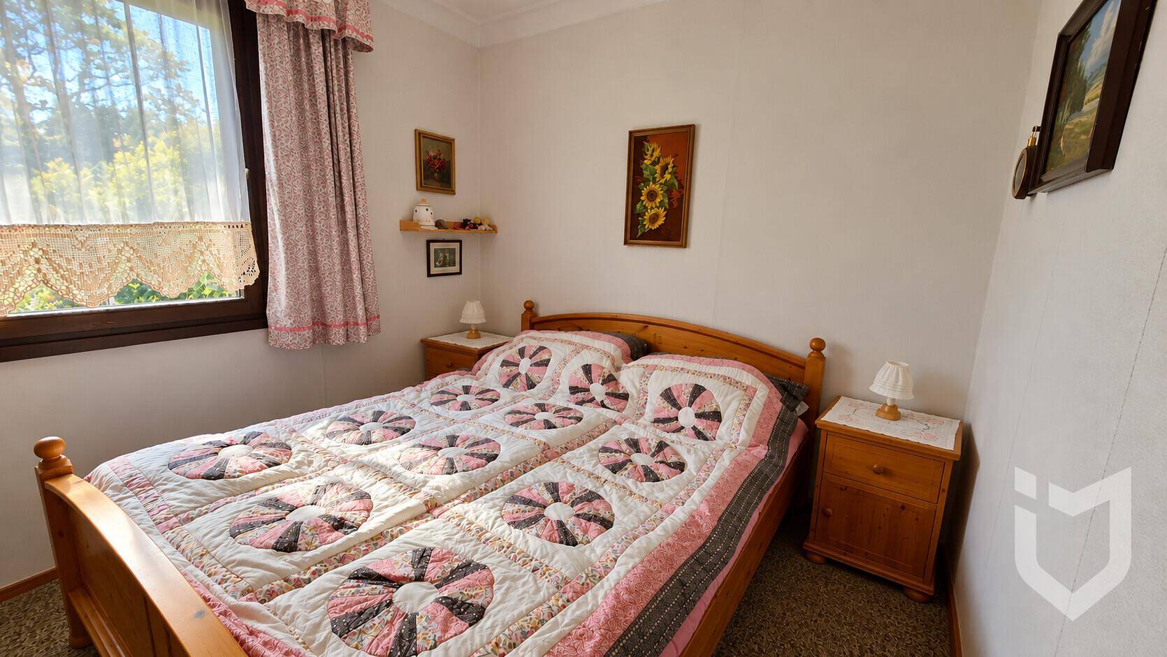 Helles Schlafzimmer mit zwei Einzelbetten, Holzmöbeln und Fenster mit Vorhängen.