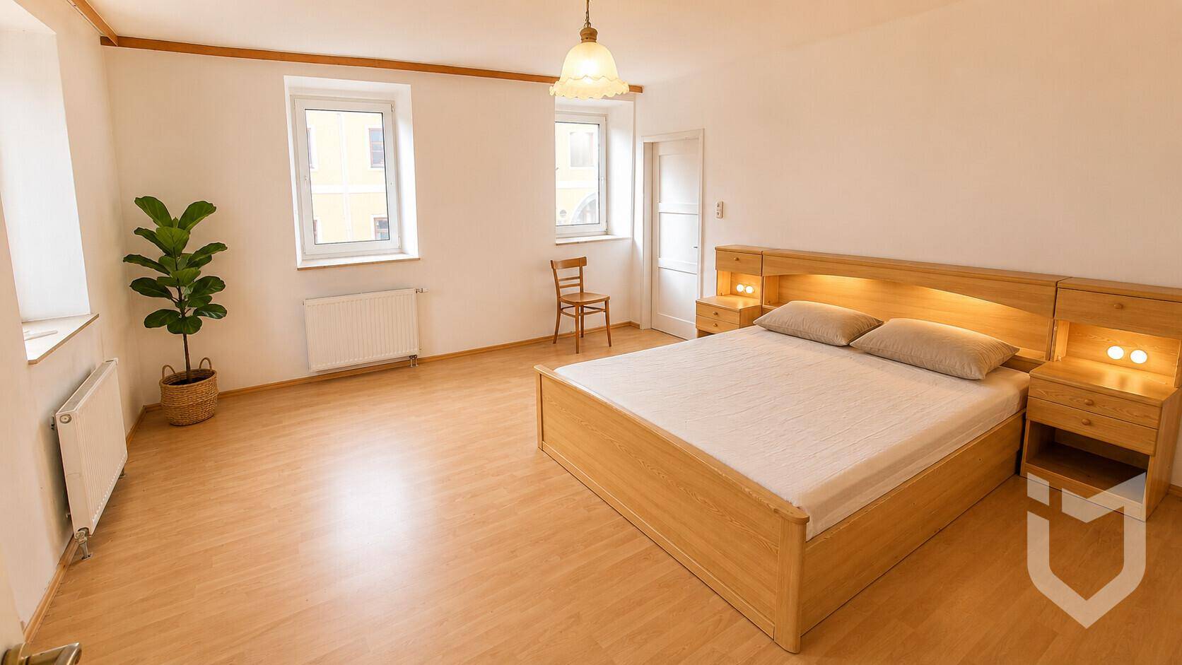 Helles Schlafzimmer mit Holzbett, Nachttischen und zwei Fenstern.