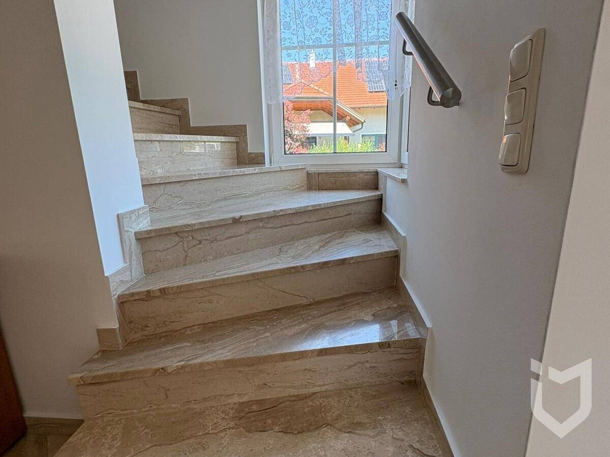 Elegante Treppe mit Marmorstufen und Handlauf, die in die obere Etage führt.