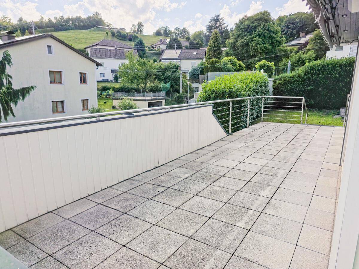Große, geflieste Terrasse mit Metallgeländer und Blick auf die umliegende Landschaft.