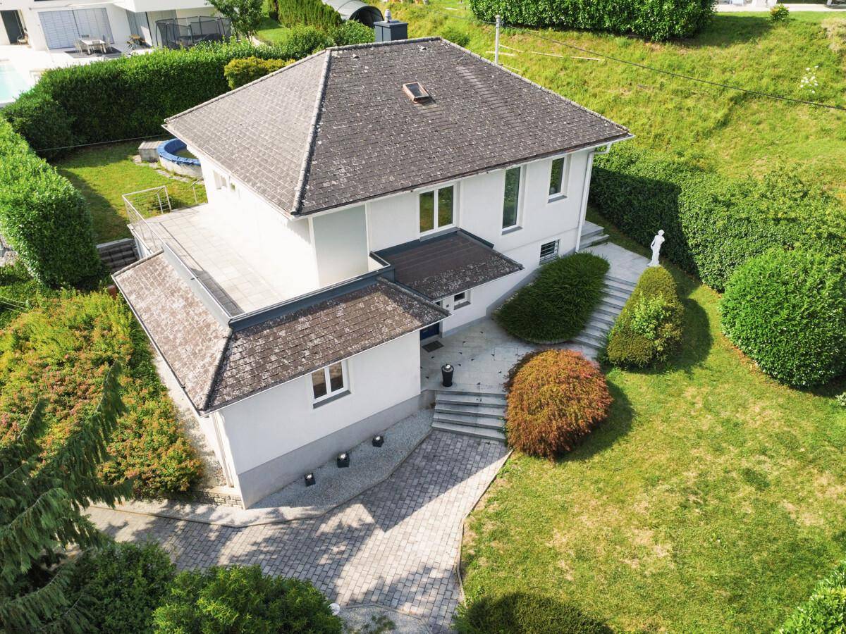 Vogelperspektive eines Einfamilienhauses mit gepflegtem Garten und Zufahrt.