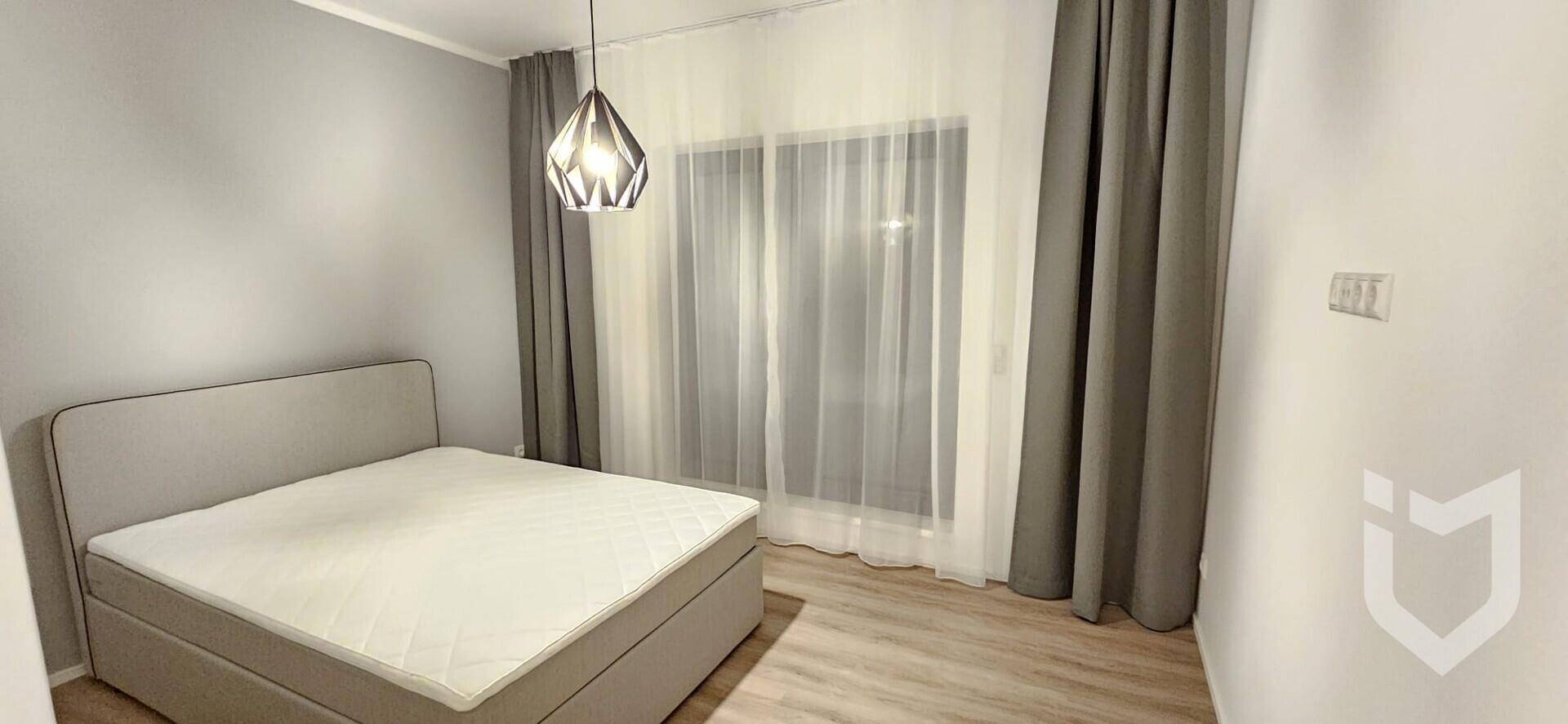Helles Schlafzimmer mit Doppelbett, modernem Licht und Zugang zum Balkon oder Terrasse.