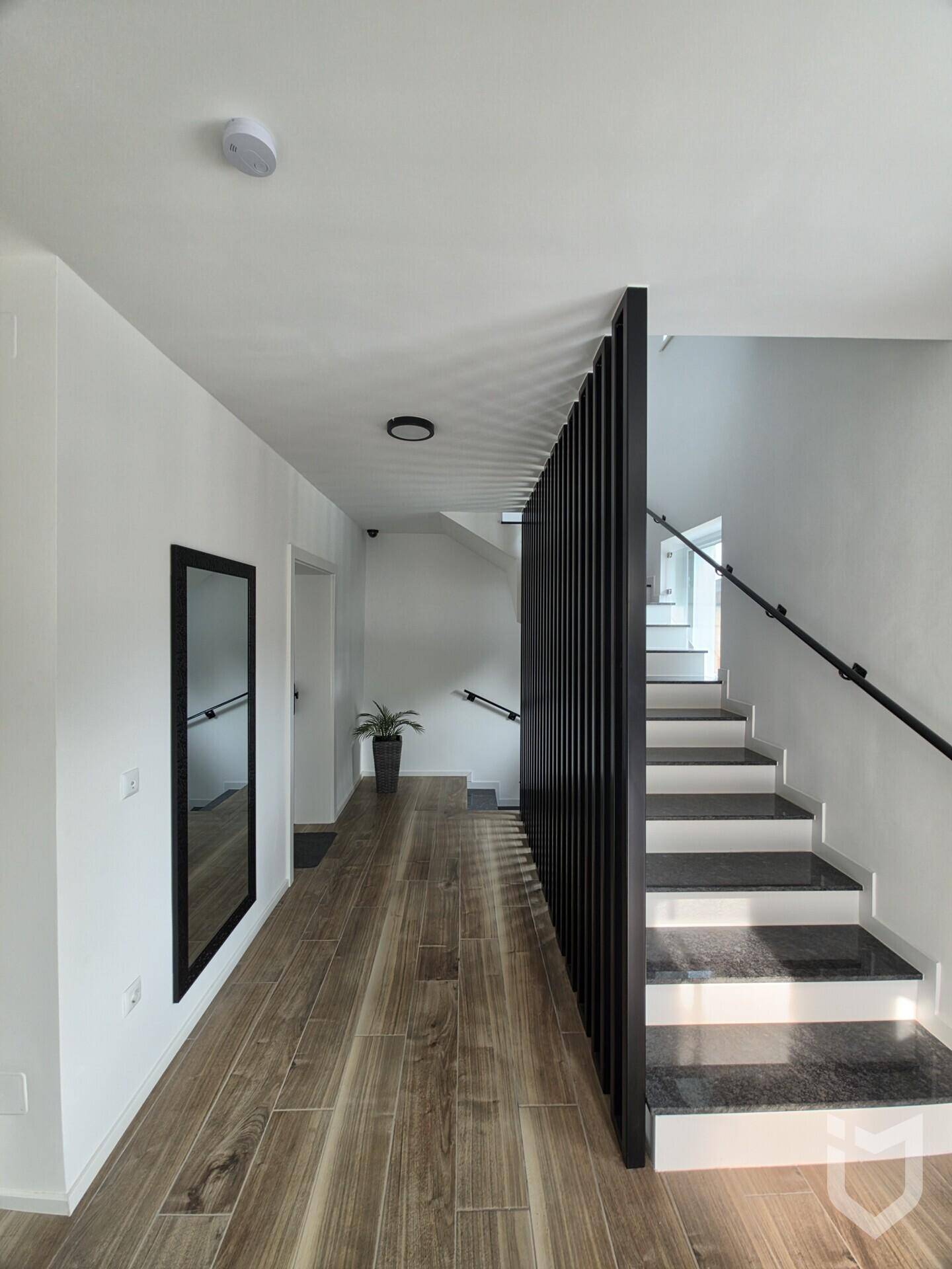 Heller Eingangsbereich mit Holzoptik-Fliesen, moderner Treppe und Spiegel.