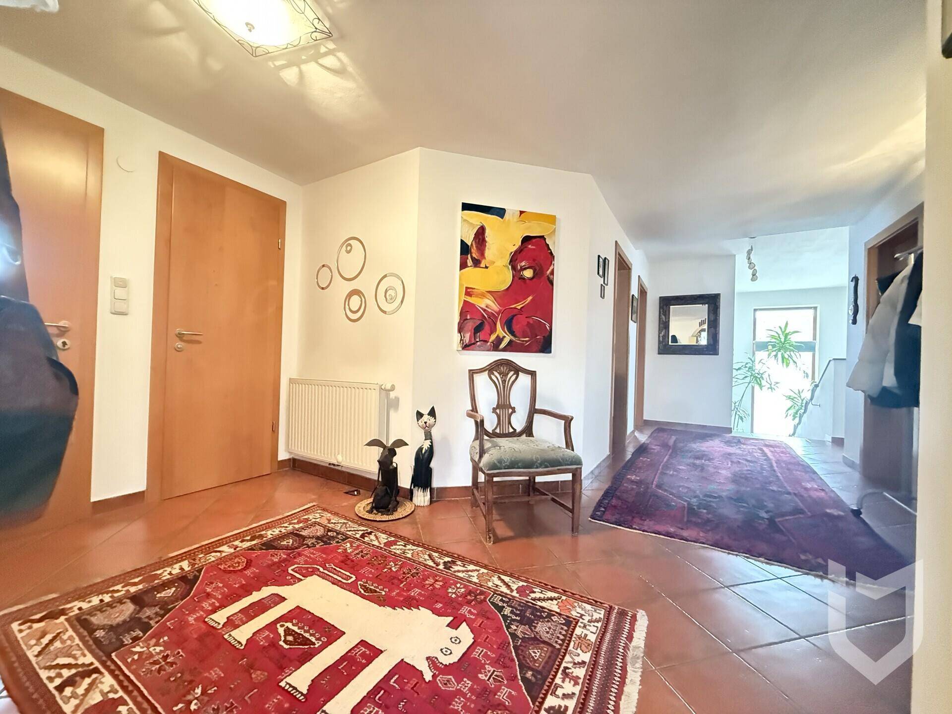 Heller Flur mit Terrakotta-Fliesenboden, Holzinnentüren und moderner Kunst an der Wand.