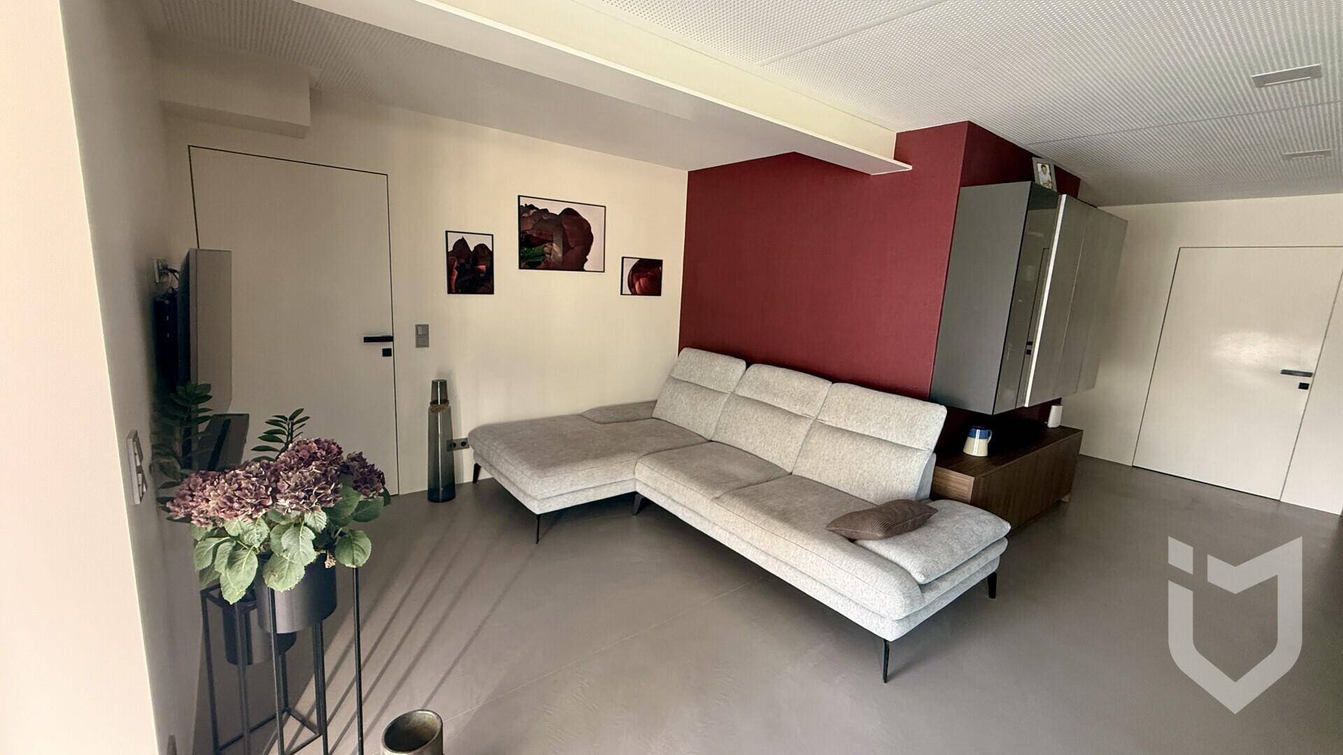 Modernes Wohnzimmer mit großem Ecksofa, Akzentwand und indirekter Deckenbeleuchtung.