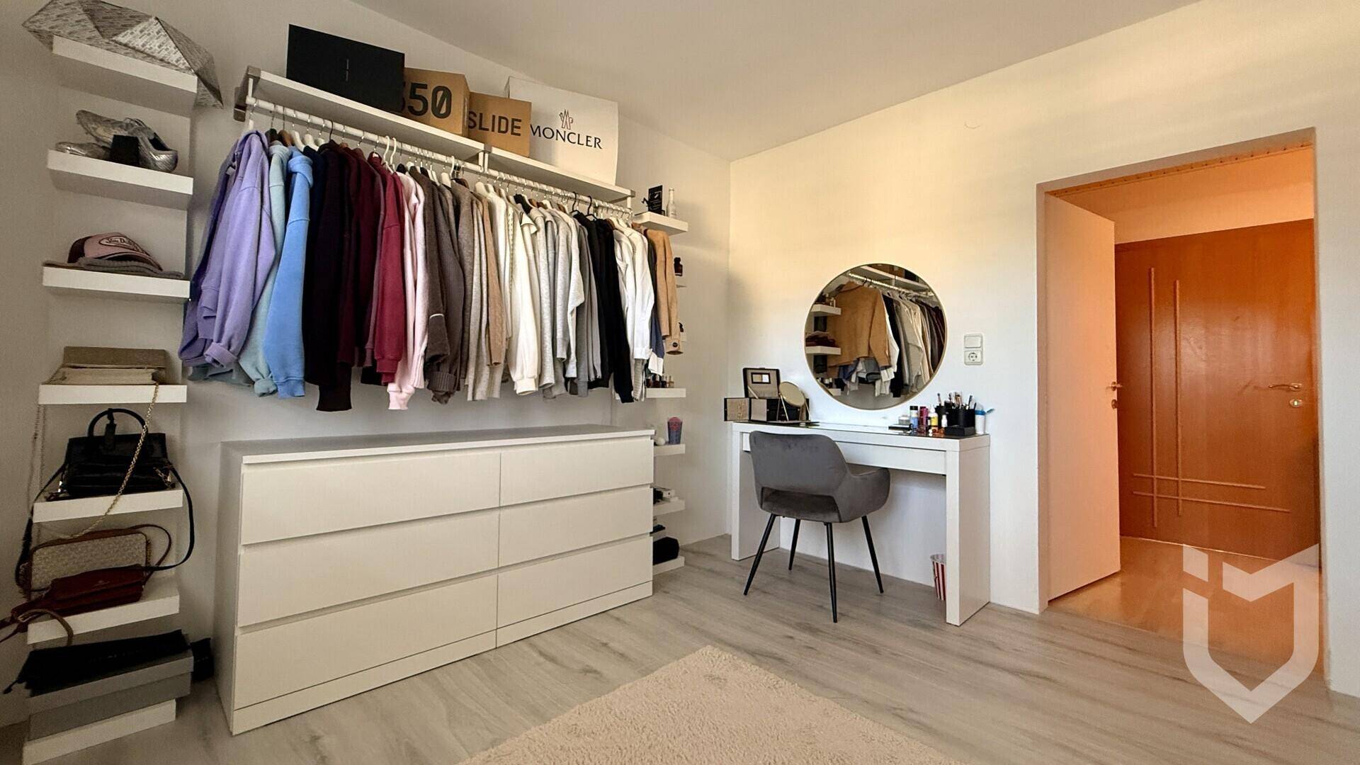 Praktischer begehbarer Kleiderschrank mit offenen Regalen, Kommode und Schminktisch.