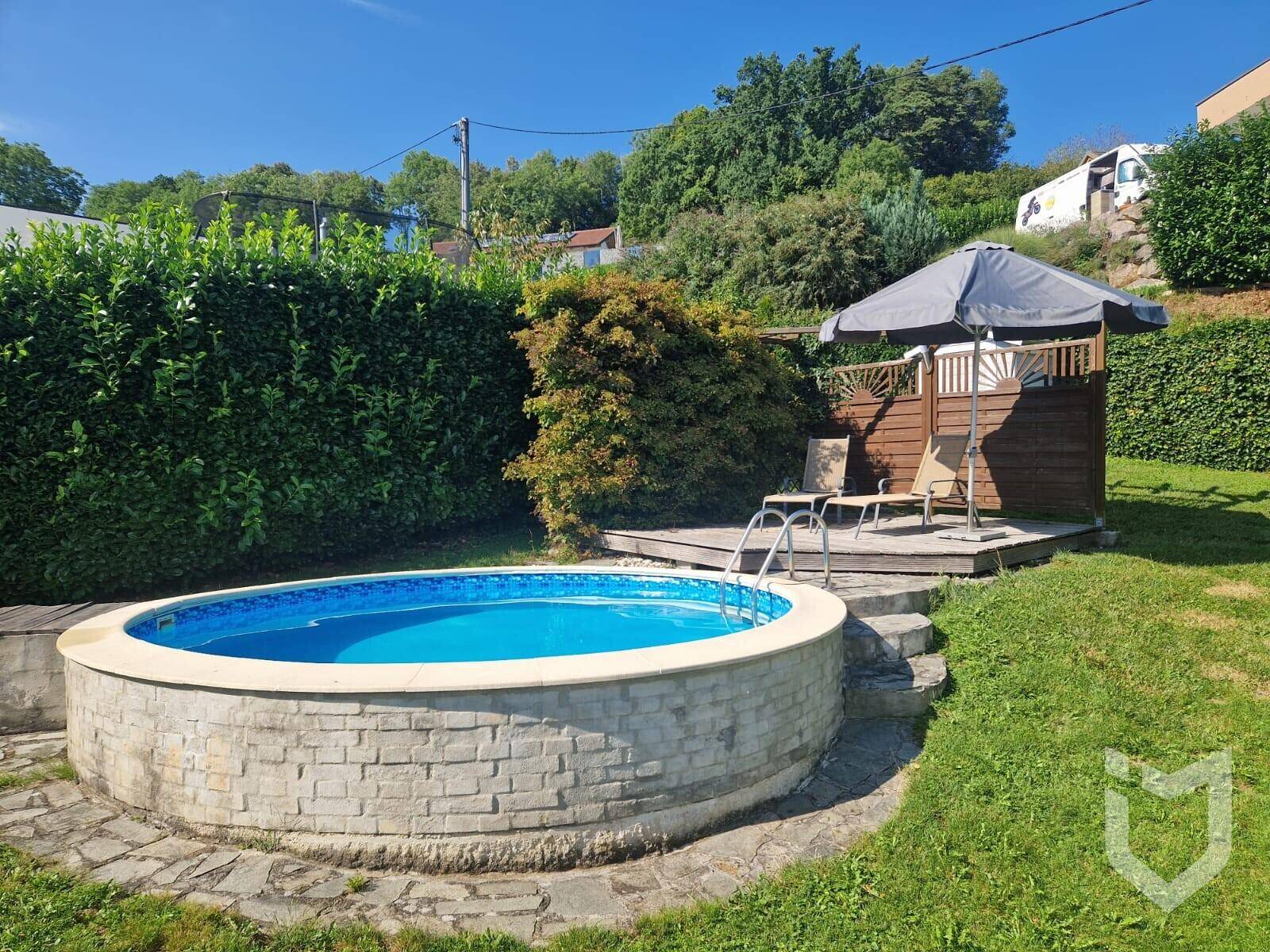 Runder Aufstellpool mit gemauerter Umrandung und angrenzendem Sitzbereich im grünen Garten.