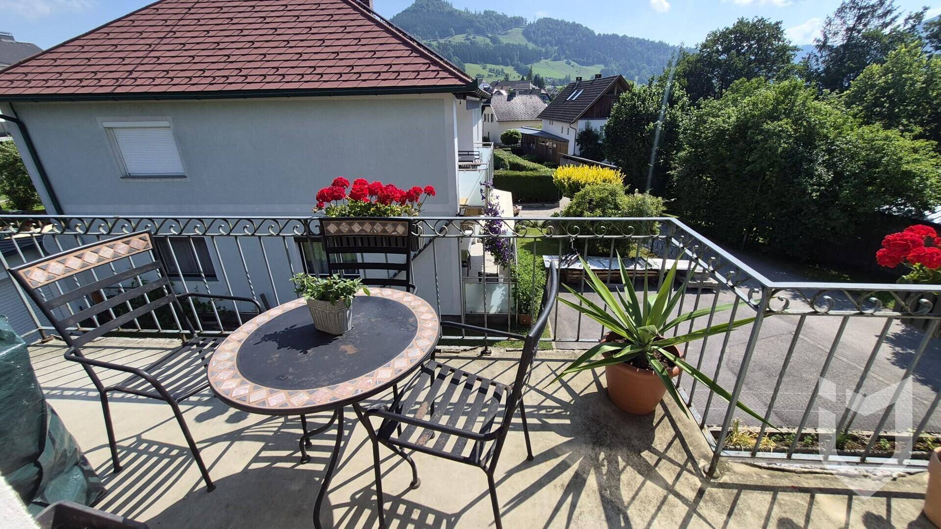 Balkon mit Sitzgelegenheiten, Pflanzen und weitem Blick auf die Berge und Umgebung.