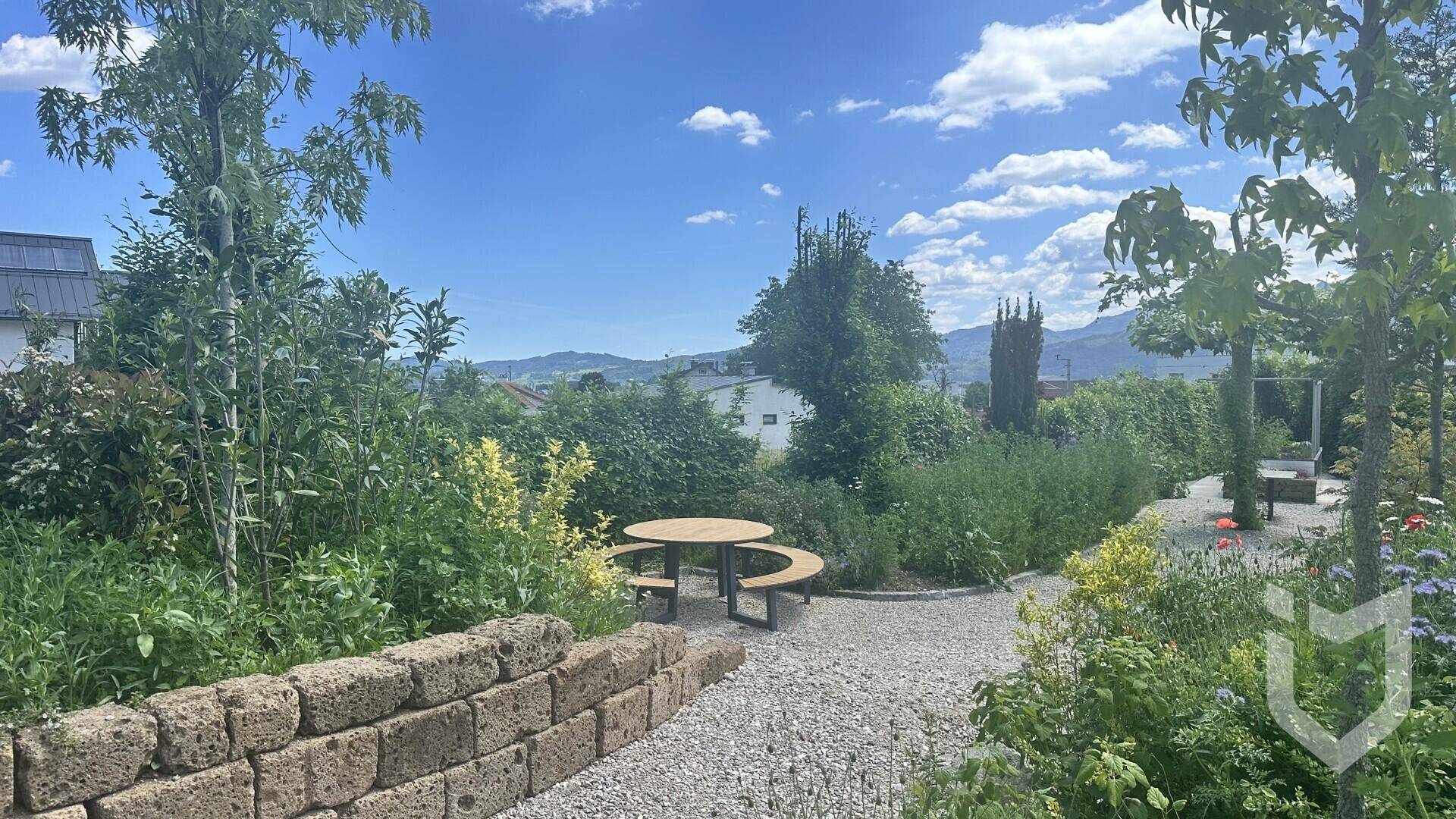 Weitläufiger Garten mit Sitzgelegenheiten, Kieswegen und üppiger Vegetation.