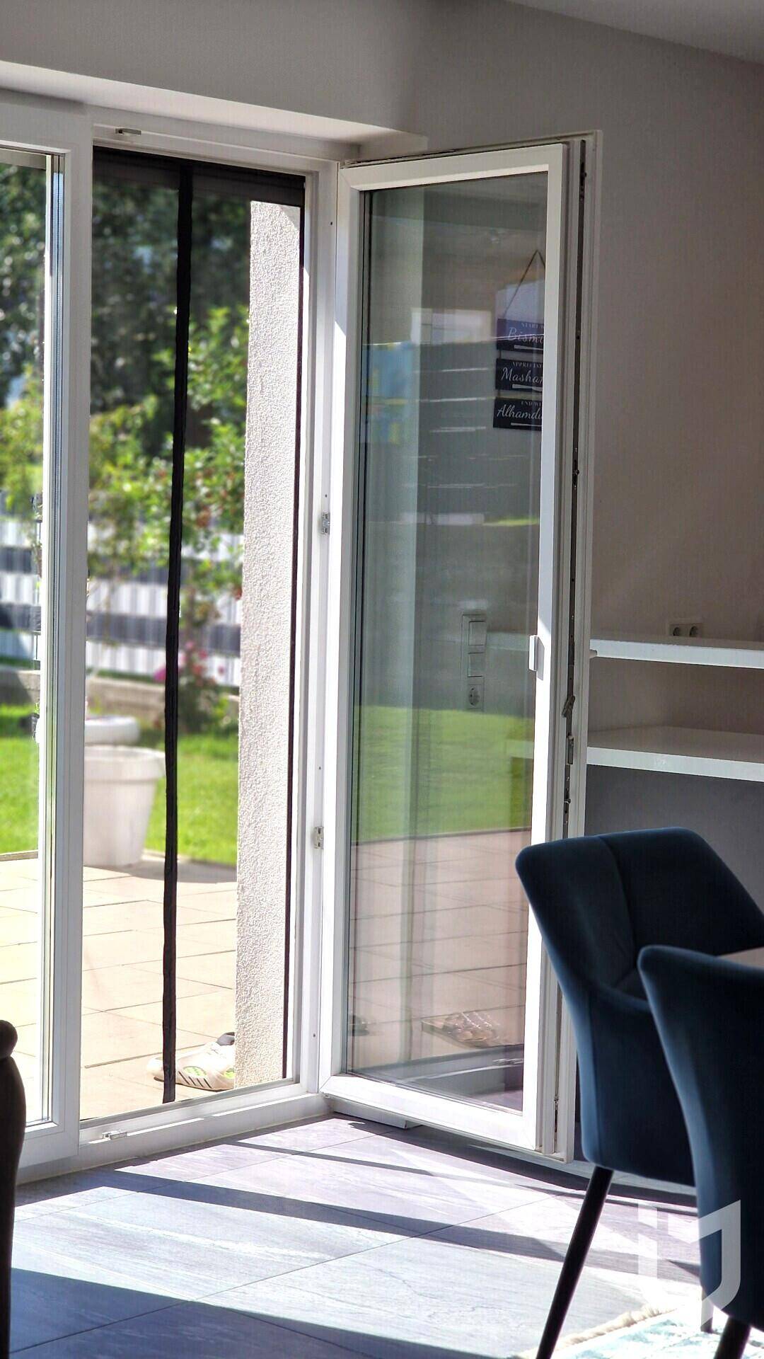 Offene Terrassentür mit Insektenschutzgitter, die den Blick in den Garten freigibt.