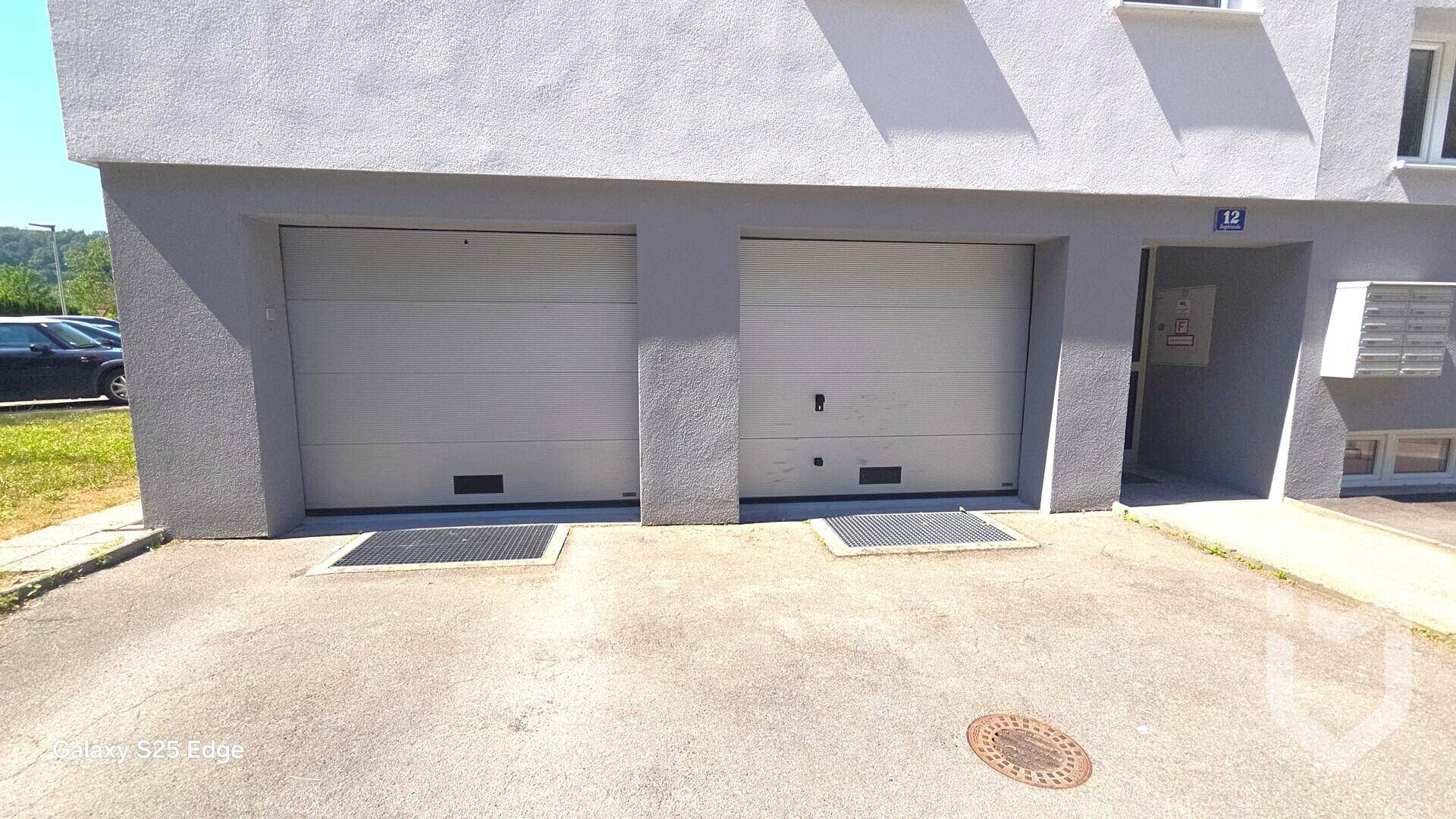 Zwei Garagentore an der Gebäudefassade, die zu den Parkplätzen der Bewohner führen.