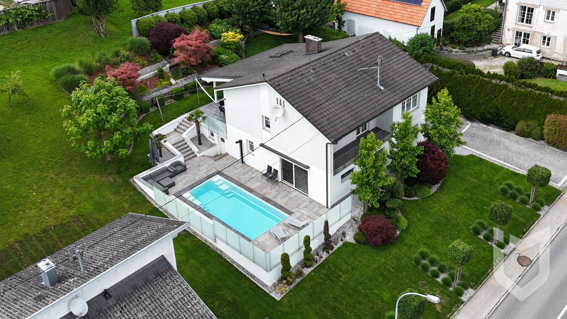 Vogelperspektive des Hauses mit modernem Poolbereich und terrassiertem, grünem Garten.