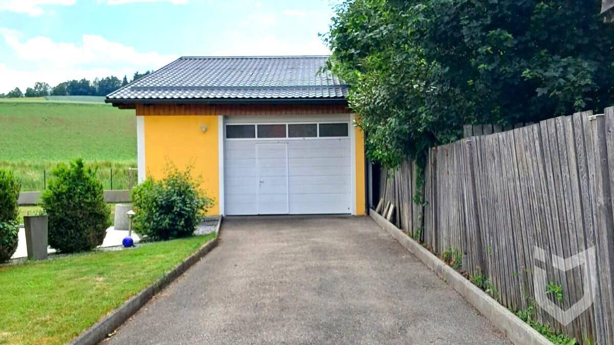 Freistehende Garage mit Einfahrt und Blick auf die umliegende grüne Landschaft.
