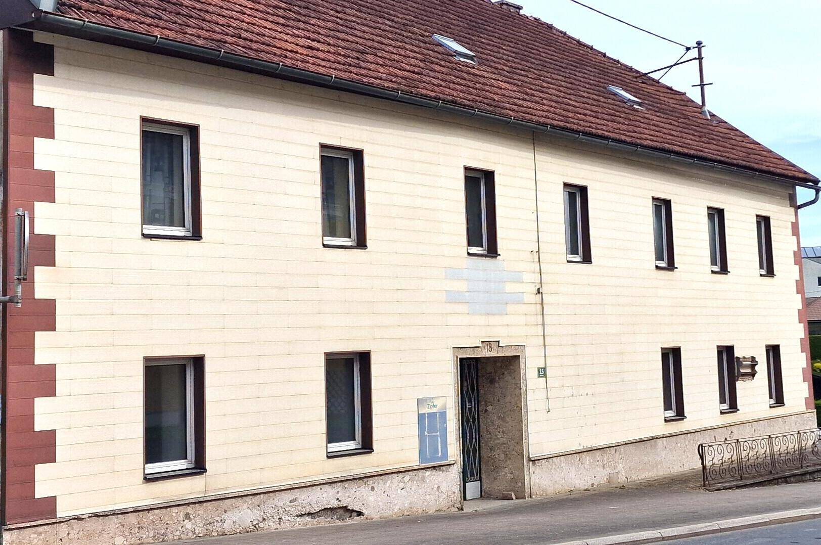 Ansicht der Hausfassade mit mehreren Fenstern und traditionellem Ziegeldach.