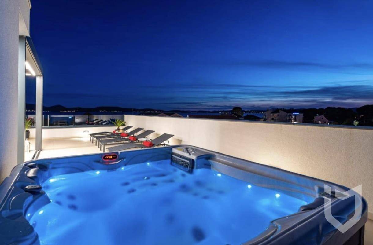 Beleuchteter Whirlpool auf der Dachterrasse bei Nacht mit ruhigem Meerblick.