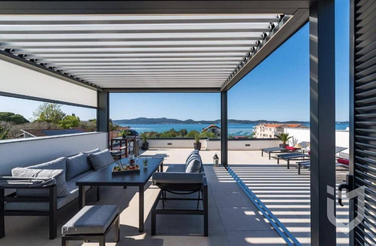 Sonnige Dachterrasse mit Pergola, Essbereich im Freien und weitem Meerblick.