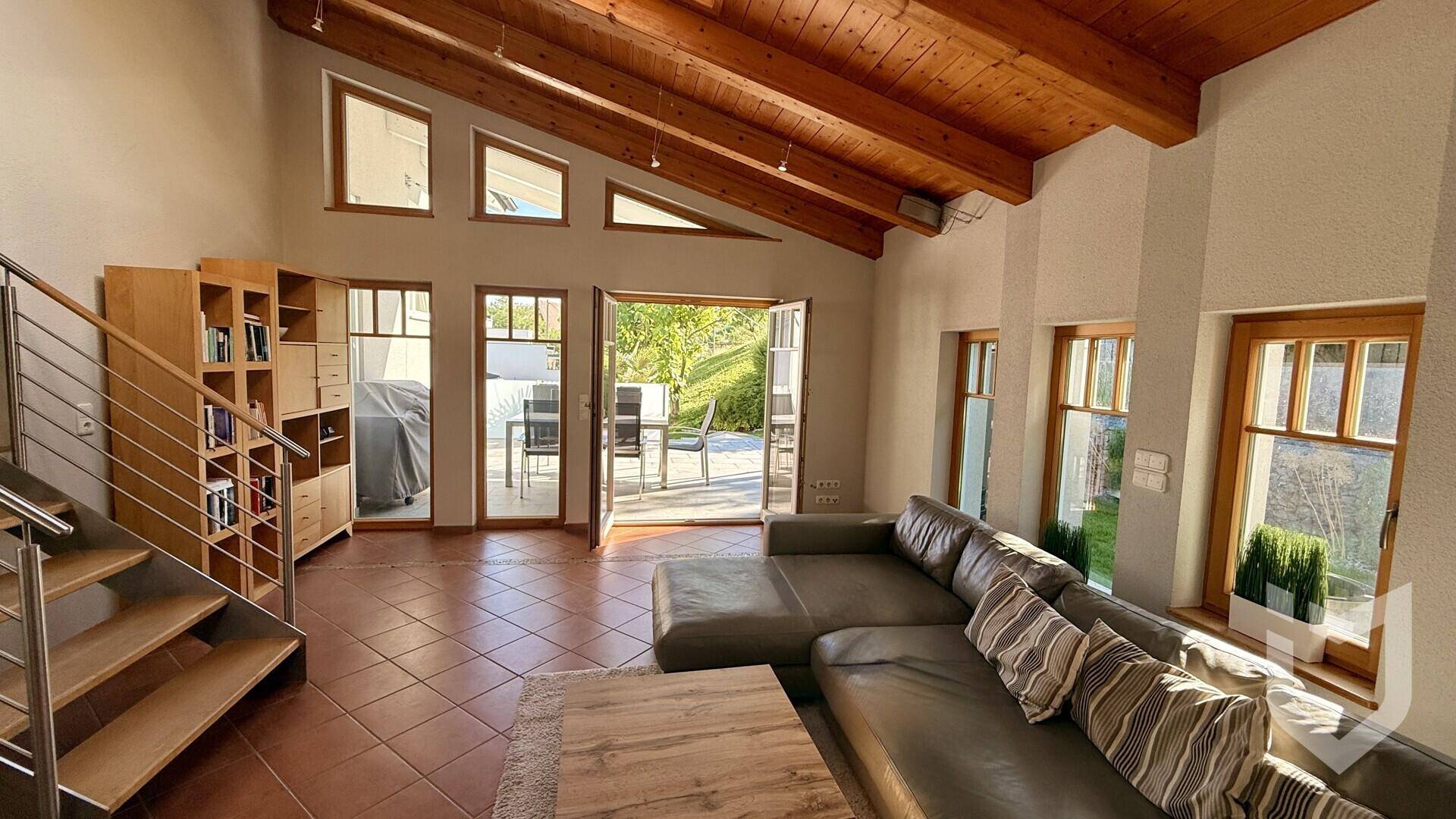 Geräumiges Wohnzimmer mit großem Sofa, Terrakottafliesen und Holzdach, mit Zugang zur Terrasse.