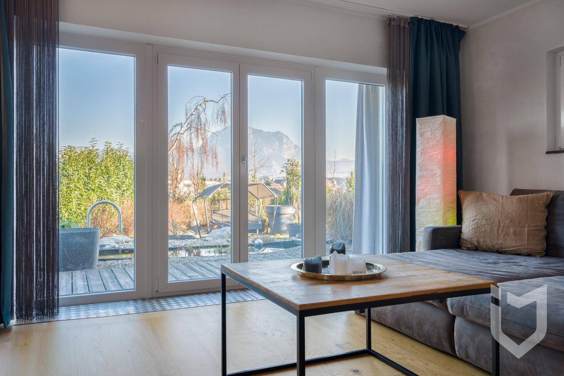 Helles Wohnzimmer mit großen Fenstern, die den Blick auf die Berge freigeben.