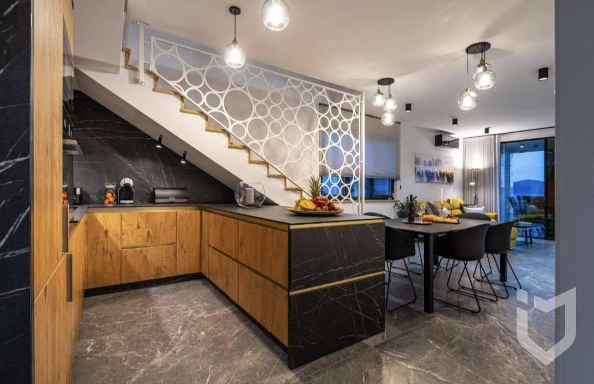 Moderne offene Küche mit Holzelementen, dunklen Arbeitsplatten und dekorativer Treppe.