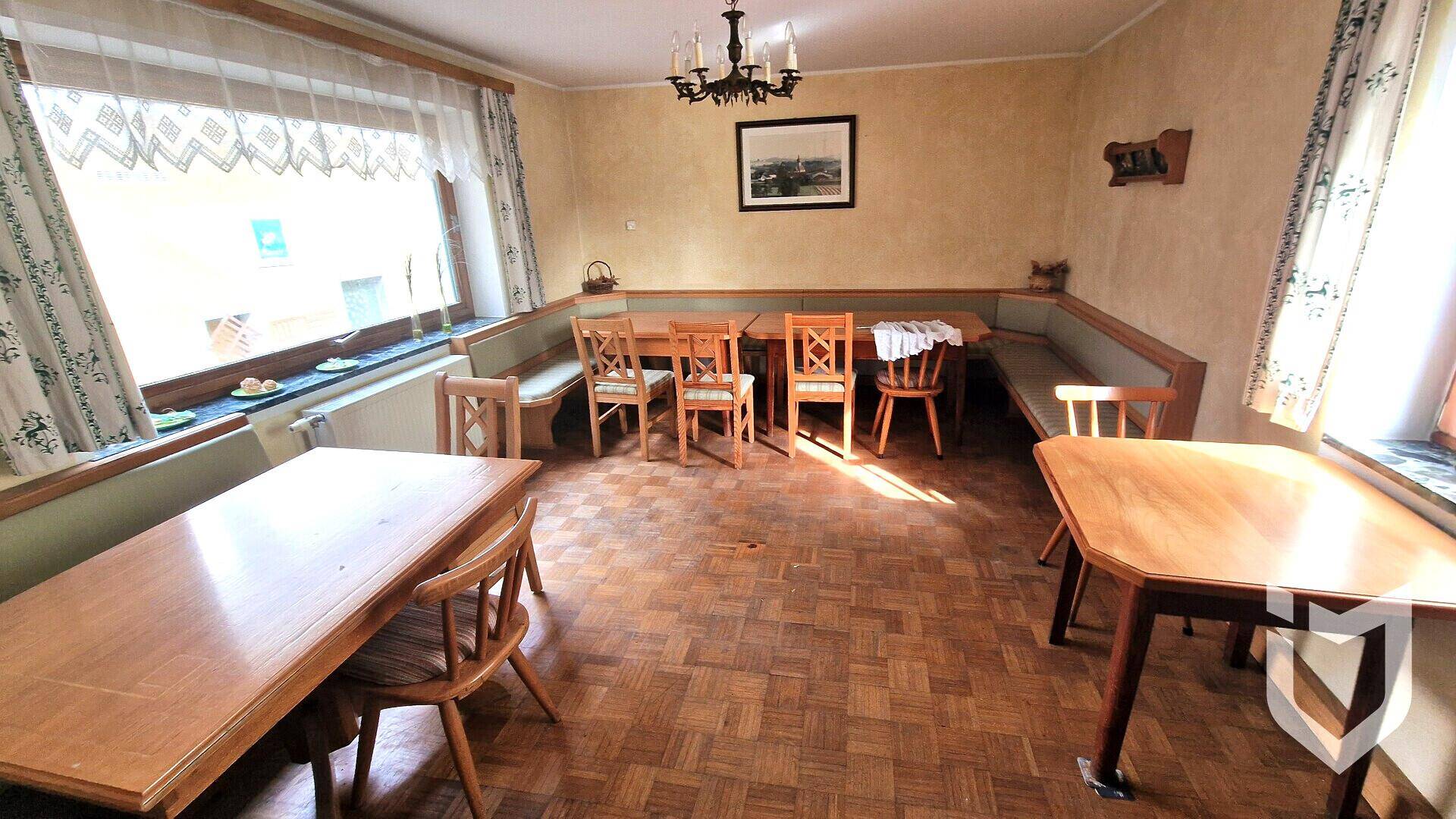 Gemütlicher Essbereich mit Holztischen, Eckbank und traditionellem Parkettboden.