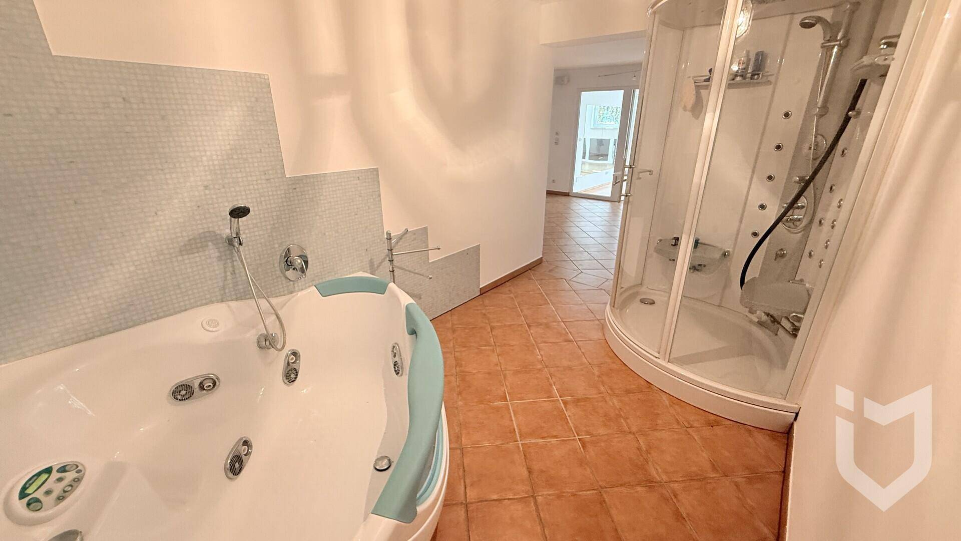 Wellnessbereich mit Whirlpool und einer modernen Duschkabine mit mehreren Massagedüsen.