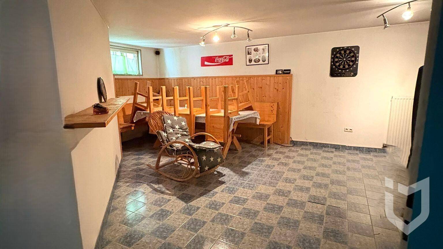 Ausgebauter Kellerraum mit Fliesenboden, Holzverkleidung und Sitzgelegenheiten.