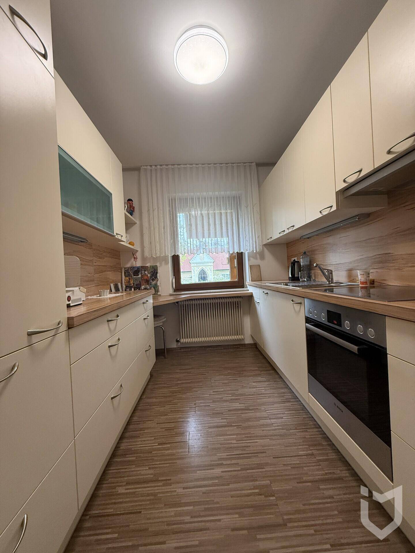 Funktionale Küche mit hellen Schränken, Holz-Arbeitsplatten und integrierten Elektrogeräten.