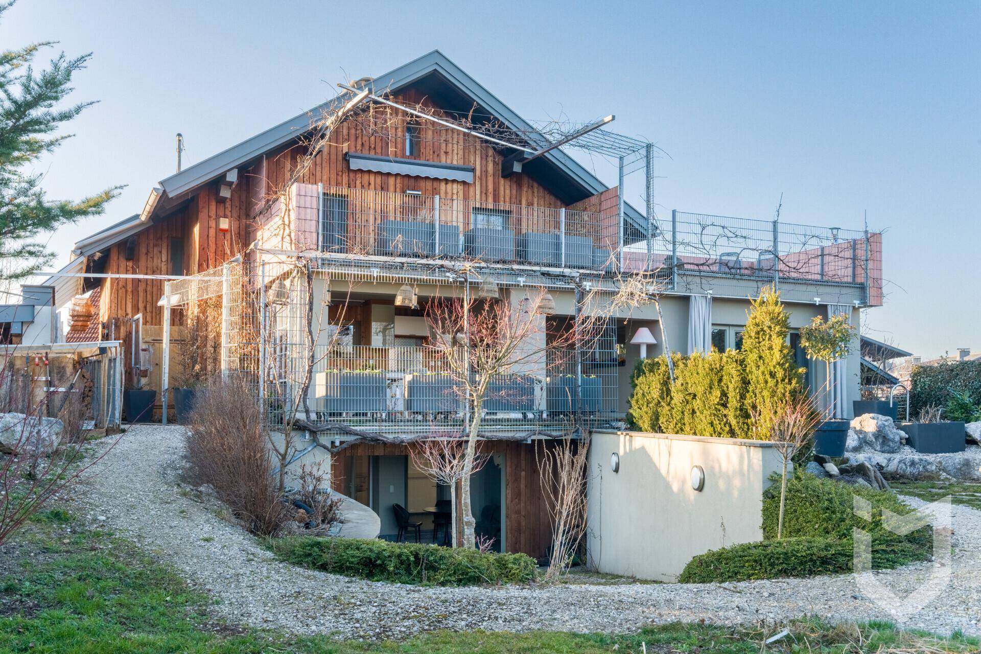 Modernes Holzhaus mit mehreren Balkonen und Terrassen in sonniger Lage.