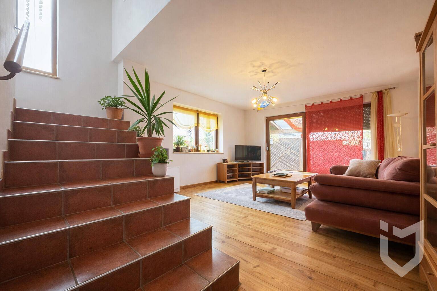 Gemütliches Wohnzimmer mit Holzboden, bequemer Couch und Zugang zu einer Außenterrasse.