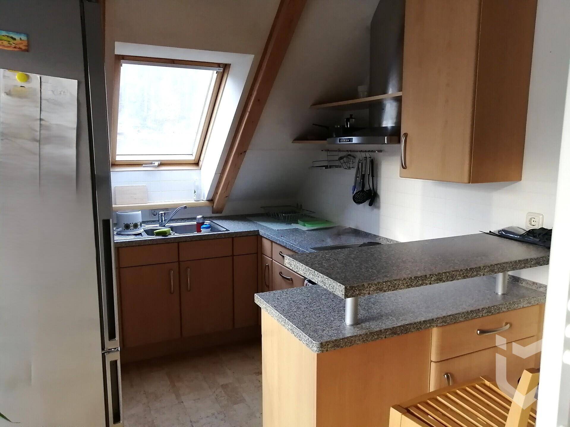 Helle Dachgeschossküche mit Granitarbeitsplatte, Dachfenster und Essbereich.