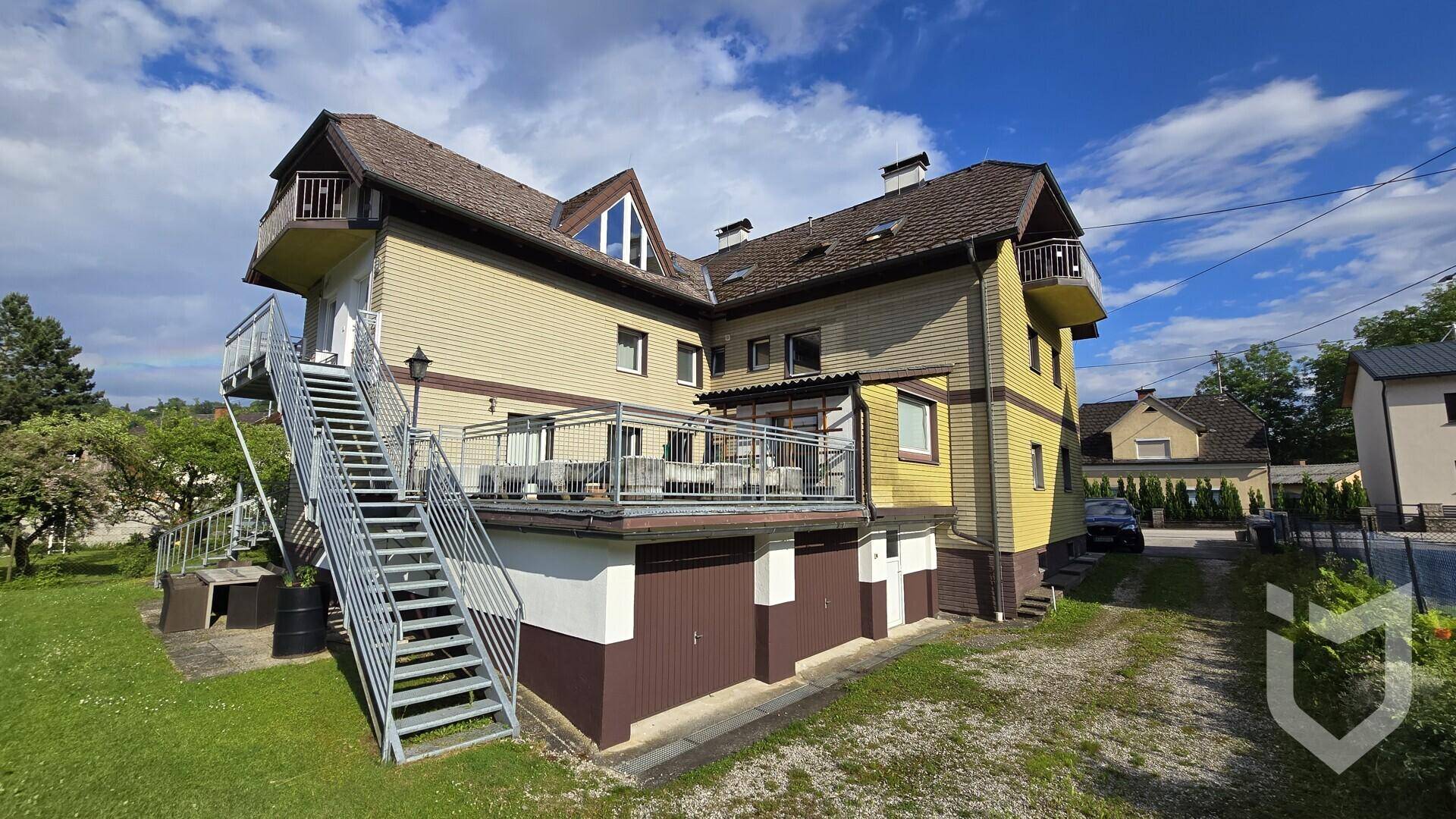 Rückansicht des Mehrfamilienhauses mit großer Terrasse und Außentreppe.