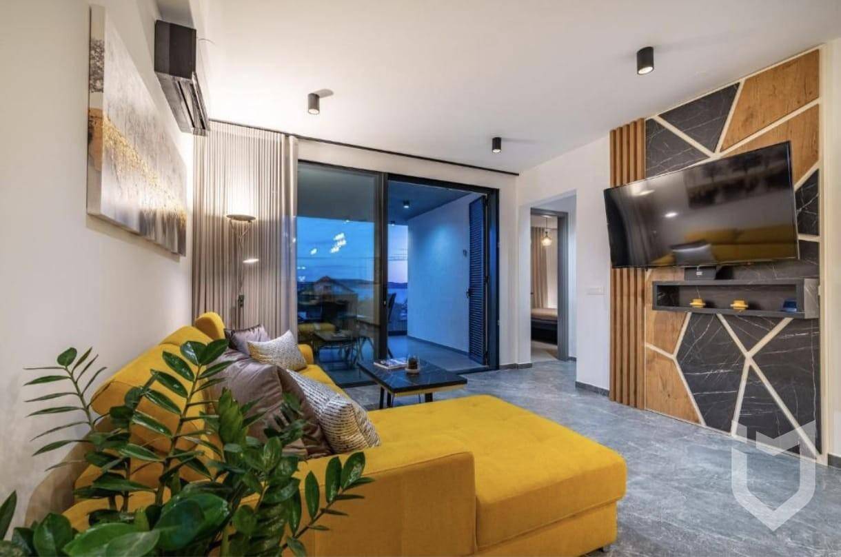 Helles Wohnzimmer mit gelbem Sofa, moderner Wandgestaltung und Zugang zur Terrasse.
