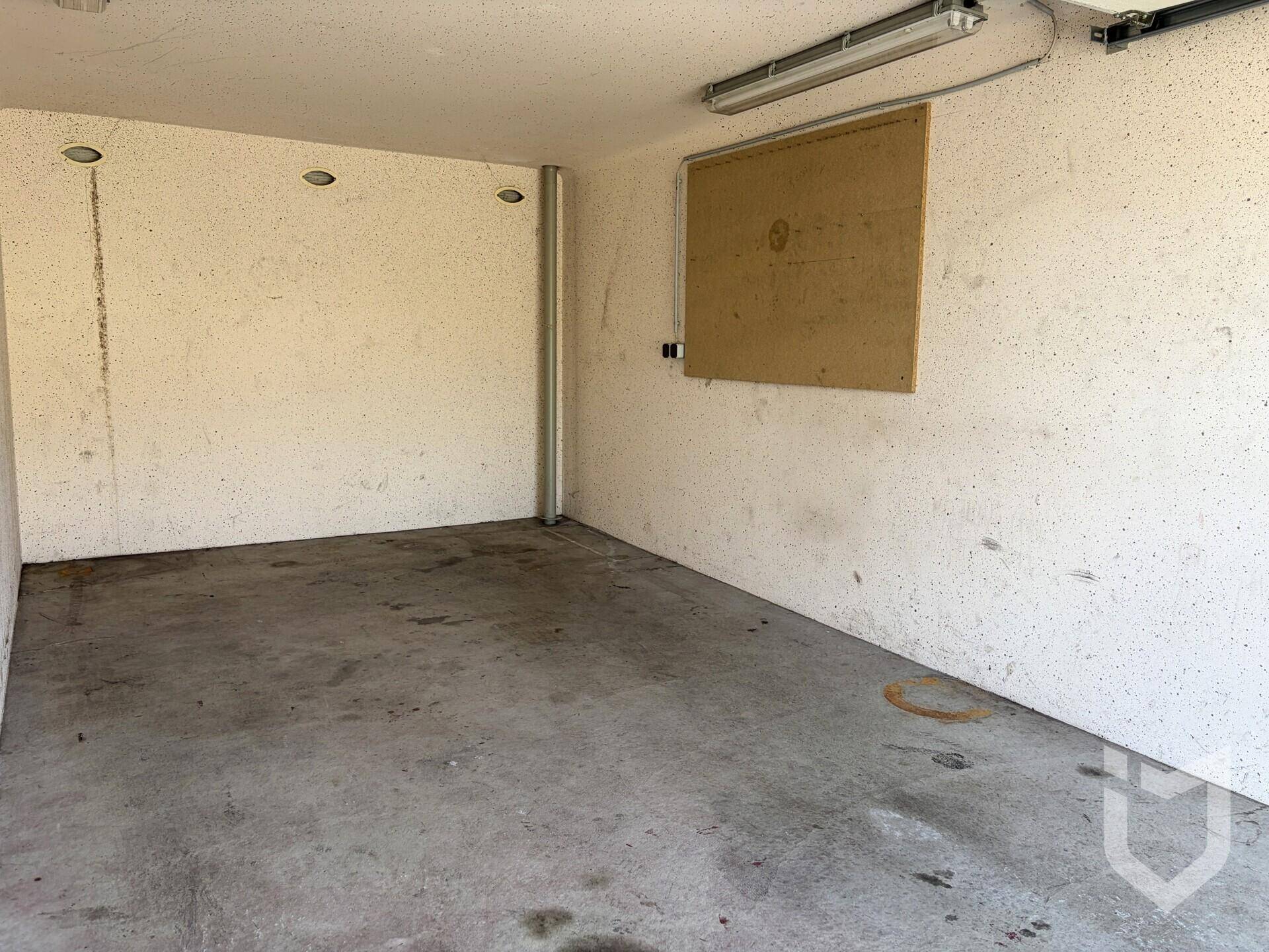 Leere Garage mit Betonboden und weißen Wänden, bereit zur Nutzung.