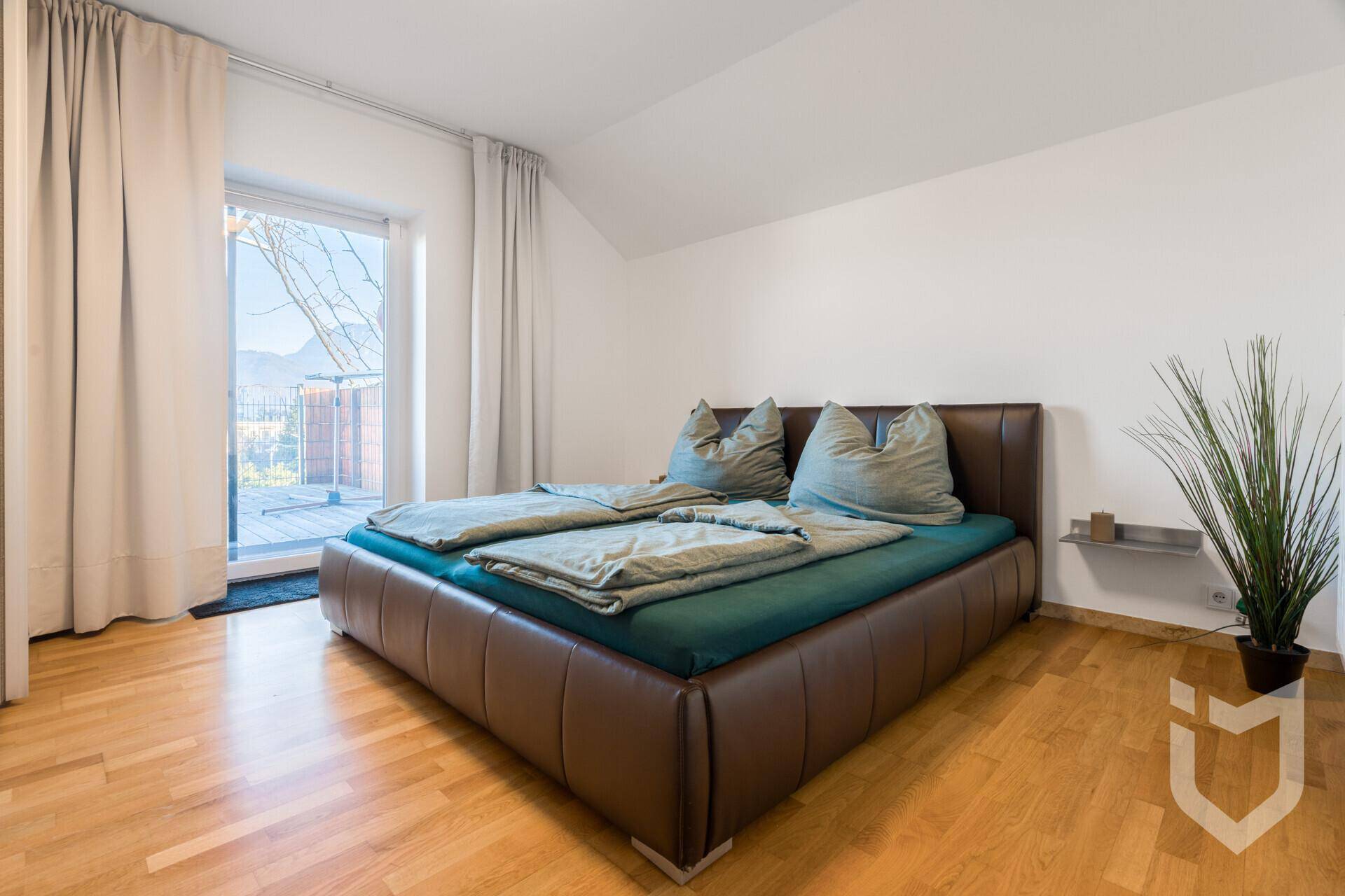 Schlafzimmer mit Doppelbett, Holzboden und Zugang zu einem Außenbereich.