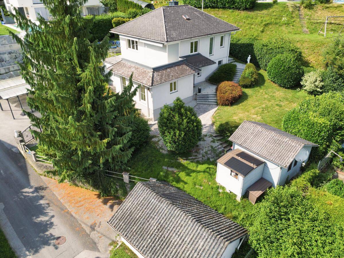 Luftaufnahme des Einfamilienhauses mit Nebengebäuden und großem, grünen Grundstück.