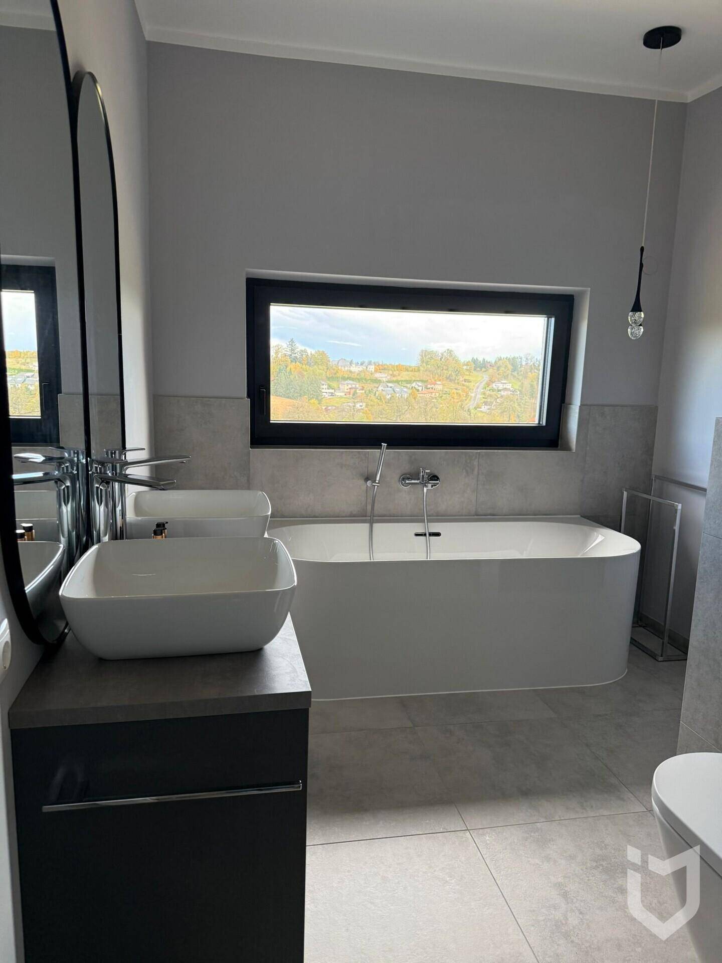Modernes Badezimmer mit freistehender Badewanne, Einzelwaschbecken und Fenster.