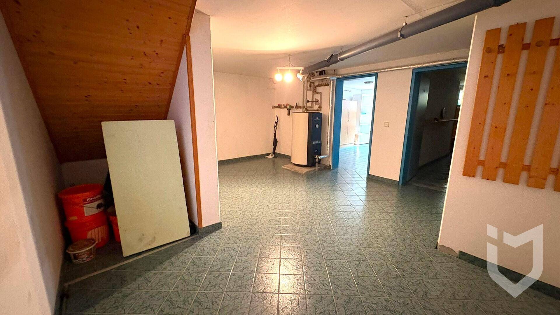 Kellerraum mit Heizungsanlage und sichtbaren Rohren, dient als Technik- und Abstellraum.