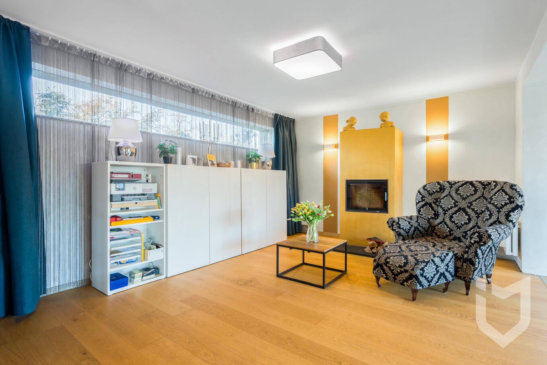 Gemütliches Wohnzimmer mit Kamin, bequemen Sessel und Holzboden.