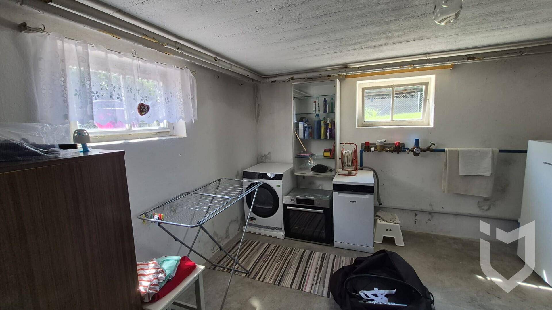 Waschküche im Keller mit Waschmaschine, Trockner und Fenstern für Tageslicht.