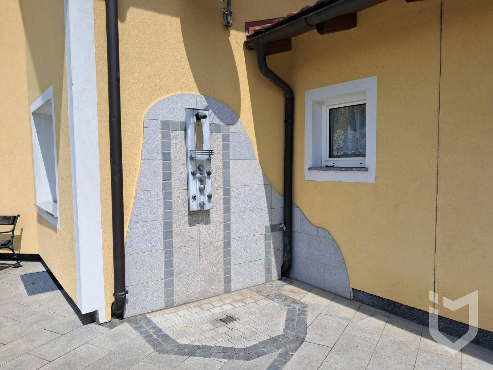 Außendusche mit modernen Fliesen und Granitverkleidung an der Hauswand.