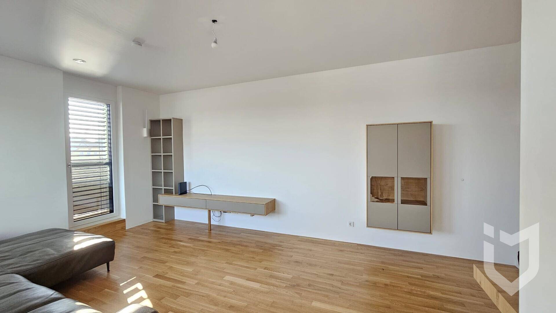 Geräumiges Wohnzimmer mit hellem Parkettboden und modernen, schwebenden Möbeln an weißen Wänden.