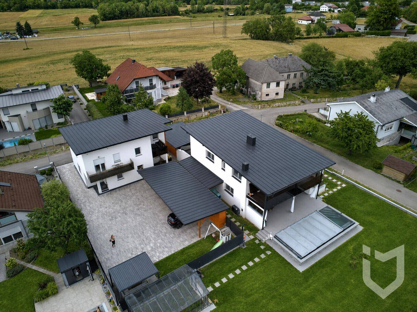 Luftaufnahme von zwei modernen Häusern mit großem Garten und integriertem Poolbereich.