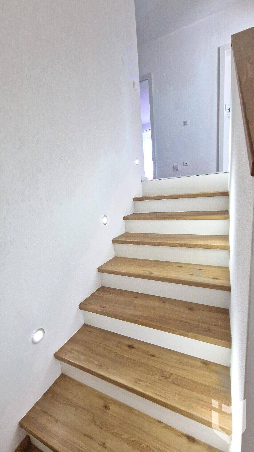 Moderne Holztreppe mit integrierter Beleuchtung, die in das obere Stockwerk führt.